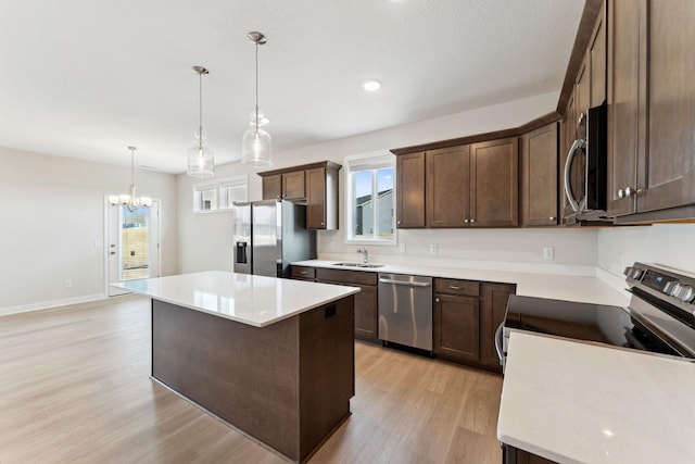 kitchen with dark brown cabinetry, a chandelier, stainless steel appliances, light wood-style floors, and a sink
