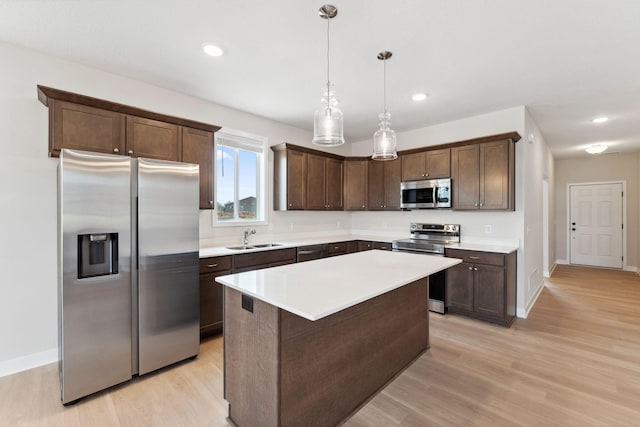 kitchen with dark brown cabinetry, a sink, light wood-style flooring, and stainless steel appliances
