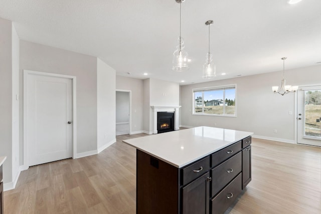 kitchen with light countertops, baseboards, a lit fireplace, and light wood-type flooring