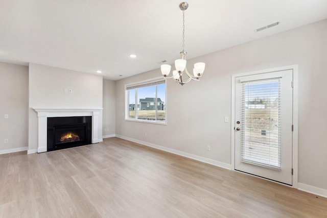 unfurnished living room featuring light wood finished floors, visible vents, a notable chandelier, and baseboards