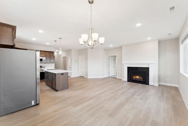 kitchen with an inviting chandelier, light wood-style flooring, stainless steel appliances, light countertops, and a kitchen island