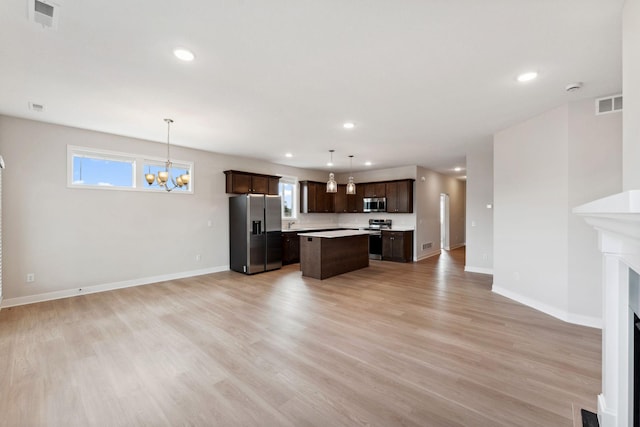 kitchen with visible vents, stainless steel appliances, a kitchen island, dark brown cabinetry, and open floor plan