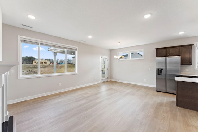 unfurnished living room featuring recessed lighting, an inviting chandelier, visible vents, light wood-style flooring, and baseboards