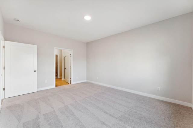 unfurnished bedroom with baseboards, recessed lighting, ensuite bathroom, and light colored carpet