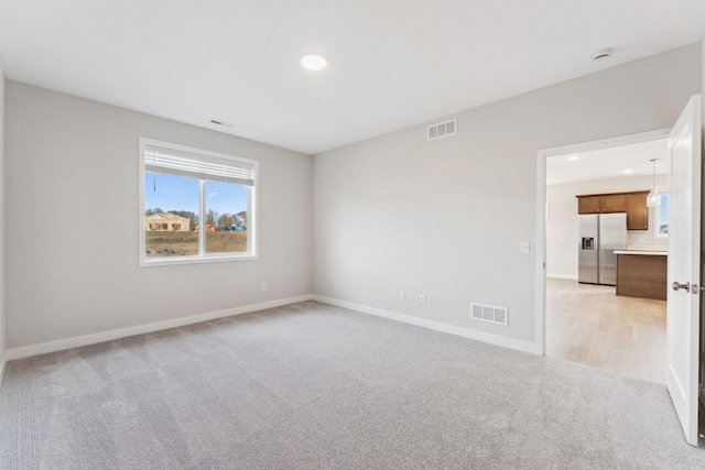 spare room with recessed lighting, visible vents, light carpet, and baseboards