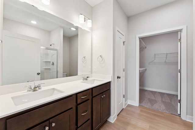 full bathroom featuring double vanity, toilet, a stall shower, and a sink
