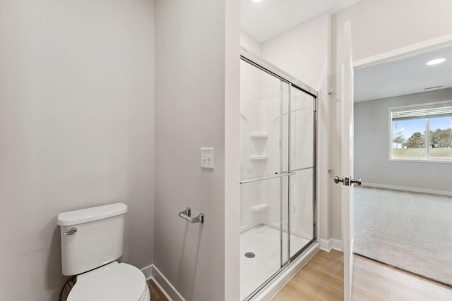 full bath featuring baseboards, wood finished floors, a shower stall, and toilet