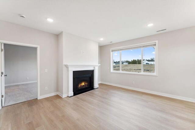 1332 Rose St, New Richmond, WI 54017 - unfurnished living room with light wood-style flooring, a fireplace with flush hearth, baseboards, and recessed lighting