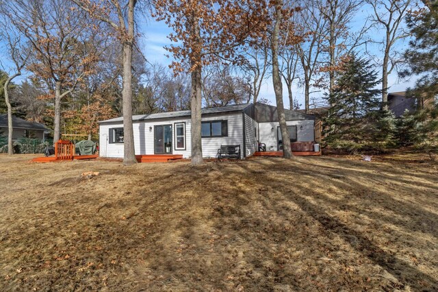 back of property with a lawn and a wooden deck