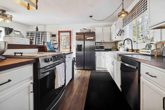 kitchen featuring wooden counters, dark wood finished floors, appliances with stainless steel finishes, white cabinetry, and a sink