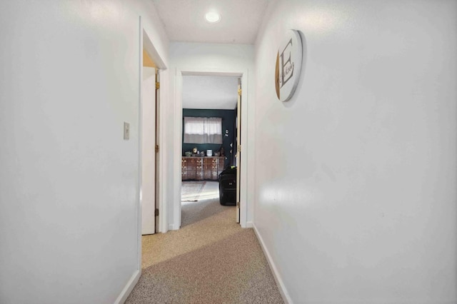 corridor featuring baseboards and carpet floors