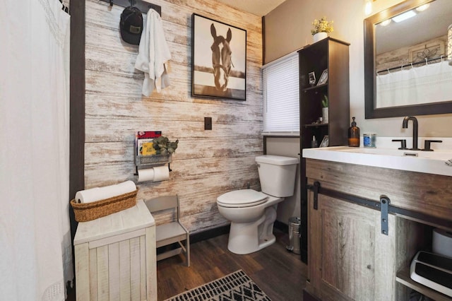 bathroom featuring vanity, wooden walls, toilet, and wood finished floors