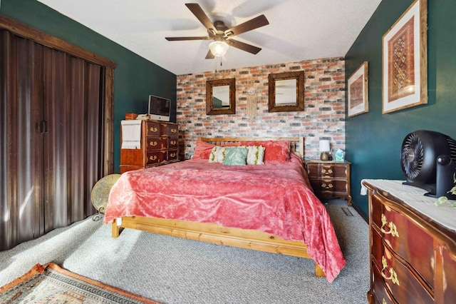 bedroom with a textured ceiling, an accent wall, carpet, and a ceiling fan