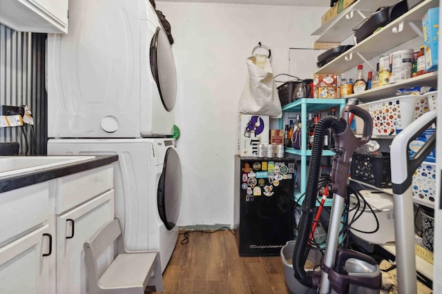 laundry area with cabinet space, stacked washer / drying machine, and dark wood-type flooring