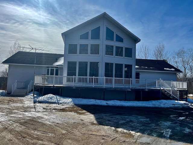 snow covered back of property featuring a deck