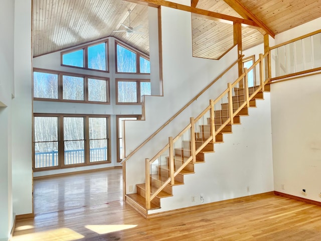 staircase featuring beam ceiling, high vaulted ceiling, wood finished floors, wooden ceiling, and baseboards