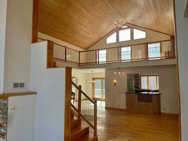 stairs with a wealth of natural light, visible vents, wooden ceiling, and wood finished floors