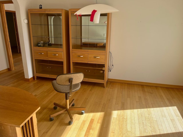 bedroom featuring baseboards, arched walkways, and light wood-type flooring