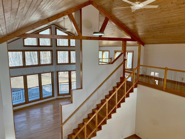 stairway with wood ceiling, beam ceiling, wood finished floors, high vaulted ceiling, and a ceiling fan