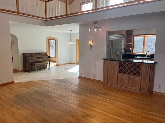 kitchen with light wood-type flooring, arched walkways, built in refrigerator, and a sink