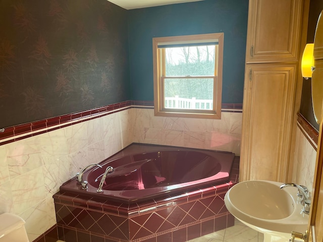 full bath featuring a garden tub and a sink