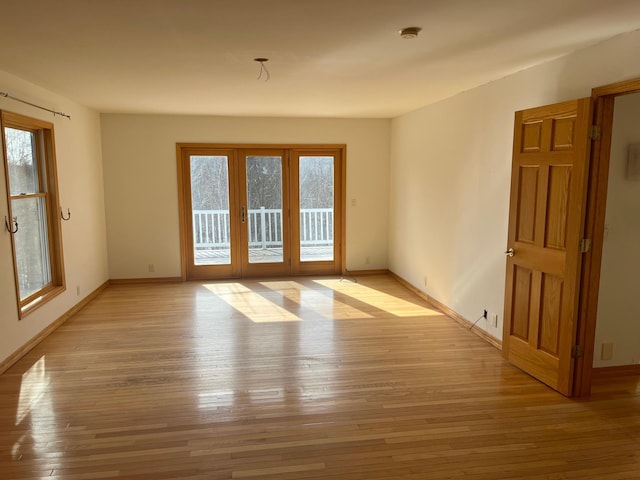 unfurnished room with a wealth of natural light, light wood-type flooring, and baseboards