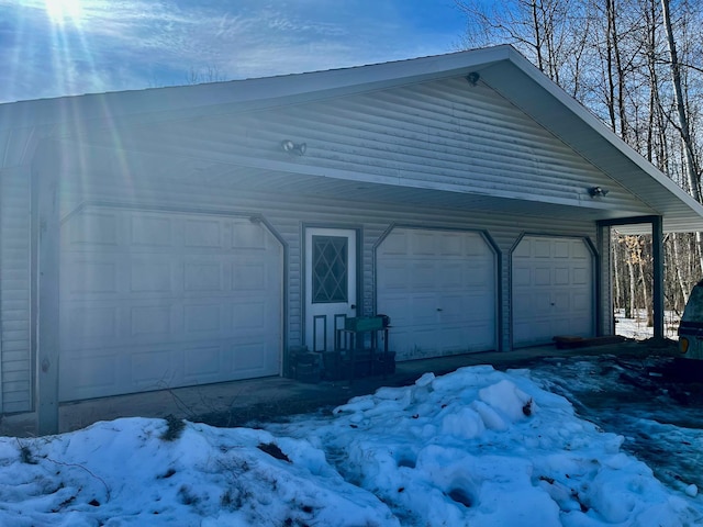 snow covered garage featuring a detached garage