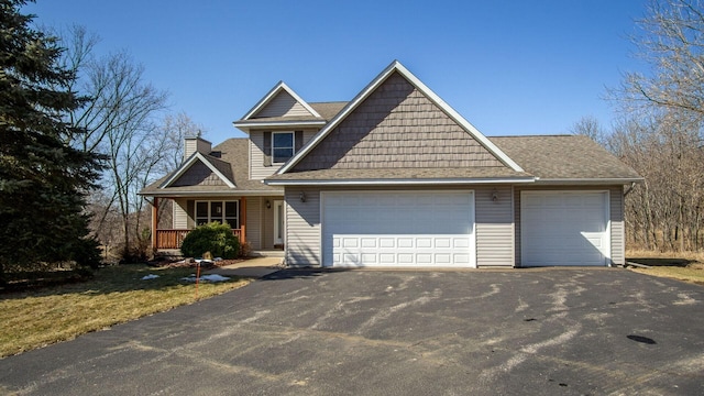 view of front of house with aphalt driveway, a porch, roof with shingles, a chimney, and a garage