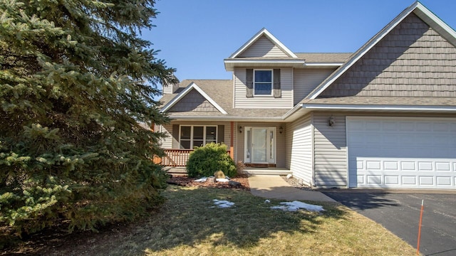 view of front of house with a front yard, roof with shingles, a chimney, a garage, and driveway