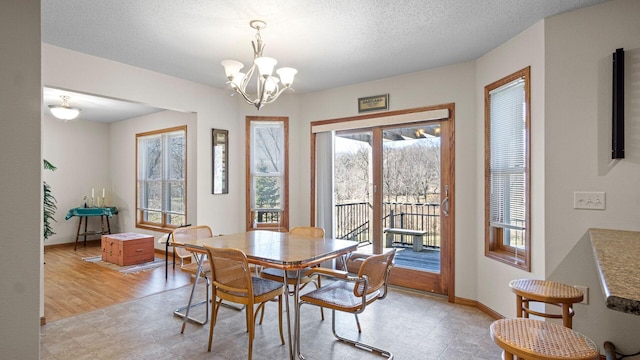 dining area featuring an inviting chandelier, a healthy amount of sunlight, baseboards, and a textured ceiling