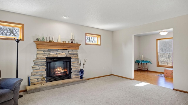 living room featuring a fireplace, baseboards, carpet floors, and a textured ceiling