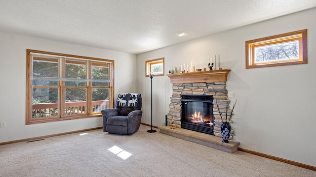 sitting room with a stone fireplace, a textured ceiling, and baseboards