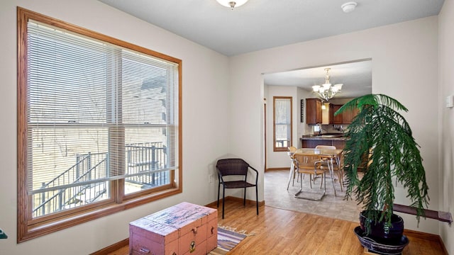 interior space with light wood finished floors, a notable chandelier, and baseboards