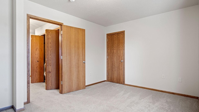 unfurnished bedroom with a textured ceiling, baseboards, and carpet floors