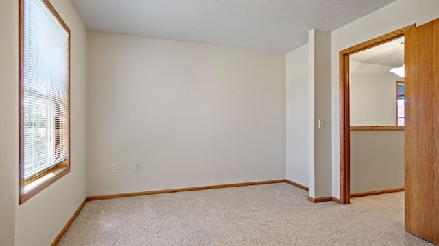 spare room with light carpet and baseboards