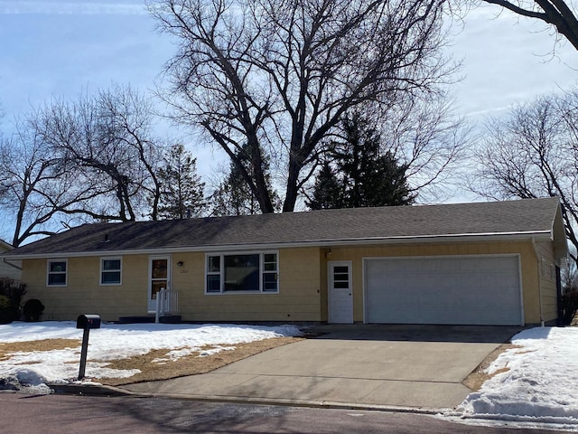 ranch-style house with concrete driveway, a garage, and roof with shingles