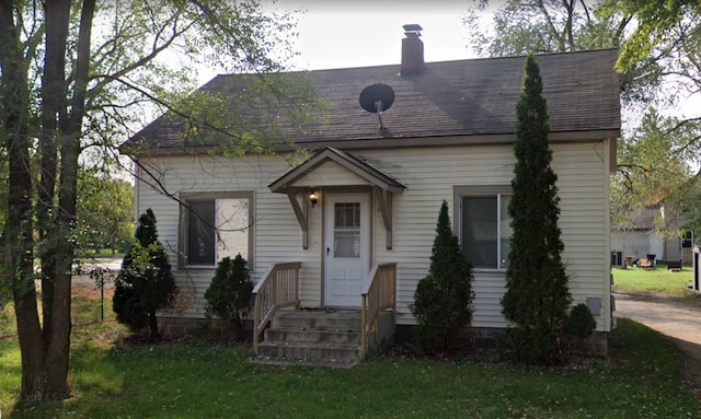 view of front of house featuring a chimney and a front yard