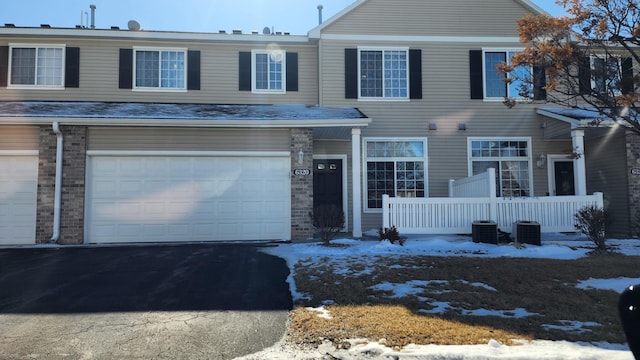 view of property with aphalt driveway, a garage, and central AC