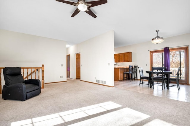 living area featuring light carpet, visible vents, ceiling fan, and baseboards