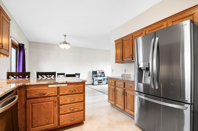 kitchen featuring light stone countertops, decorative light fixtures, brown cabinets, a peninsula, and stainless steel appliances