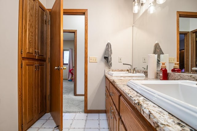 full bath featuring tile patterned floors, baseboards, double vanity, and a sink