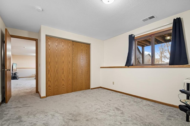 unfurnished bedroom featuring visible vents, a textured ceiling, a closet, carpet flooring, and baseboards