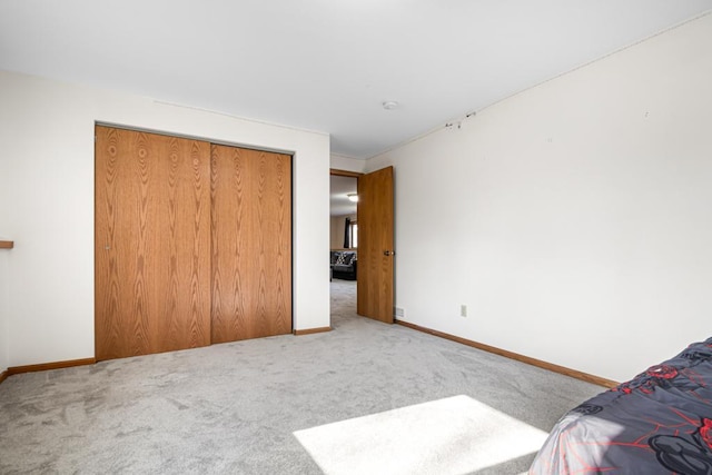 unfurnished bedroom featuring carpet flooring, baseboards, and a closet