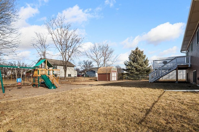 view of yard featuring an outbuilding, stairway, fence, a storage unit, and a playground