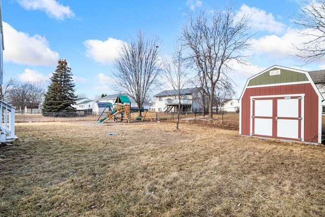 view of yard with an outbuilding, a shed, a playground, and fence