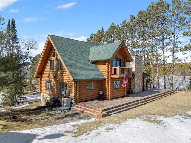 view of front of home featuring log siding, central air condition unit, a balcony, and roof with shingles