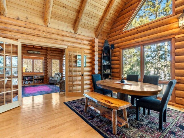 dining space featuring a healthy amount of sunlight, beam ceiling, light wood-style flooring, wooden ceiling, and high vaulted ceiling