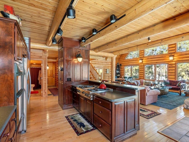 kitchen with dark countertops, track lighting, open floor plan, light wood-style floors, and stainless steel gas stovetop