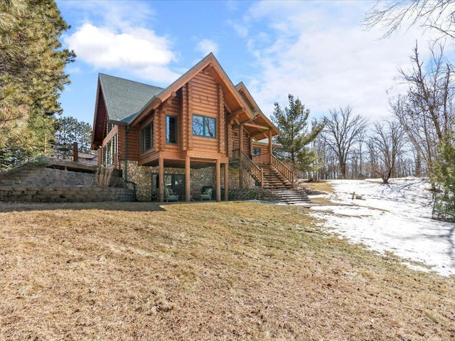 back of house featuring log siding, stone siding, a lawn, and stairs