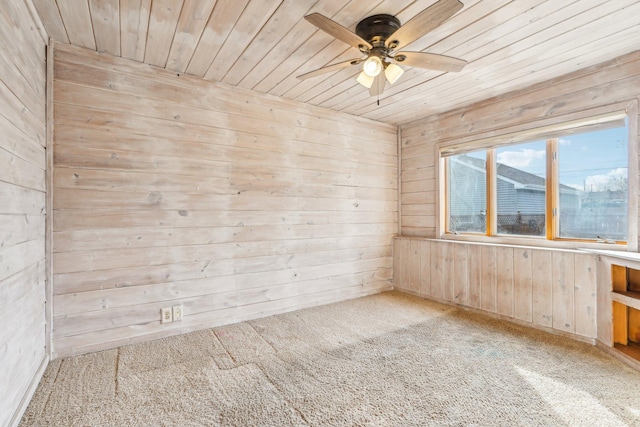 carpeted spare room with wooden walls, wood ceiling, and ceiling fan